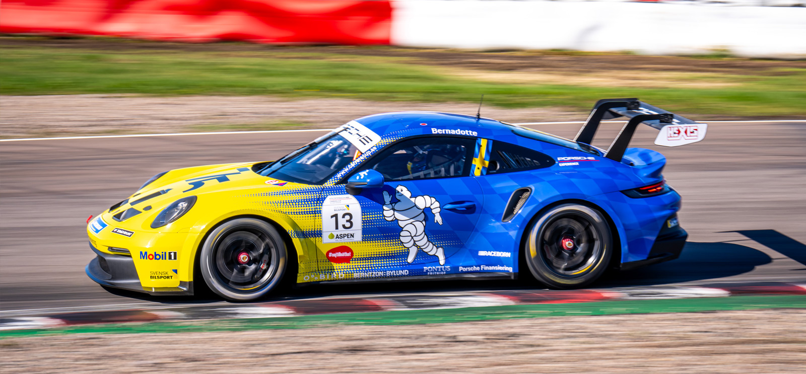 En blågul Porsche i full fart på motorbanan i Carrera Cup.
